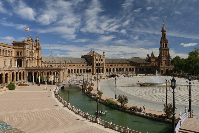 La maestosa Plaza de España di Siviglia con i suoi caratteristici ponti in ceramica, il semicerchio di edifici in stile rinascimentale e neomudéjar, e il canale dove navigano piccole barche, simbolo dell'Andalusia