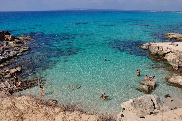 Vista aerea delle acque cristalline turchesi di Formentera, con la sabbia bianca che contrasta con il blu intenso del Mediterraneo, esempio della bellezza incontaminata delle Isole Baleari